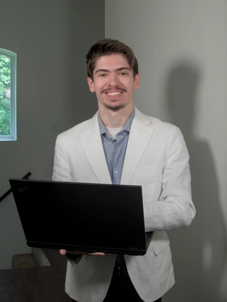 Andrew Neal holding a laptop and smiling